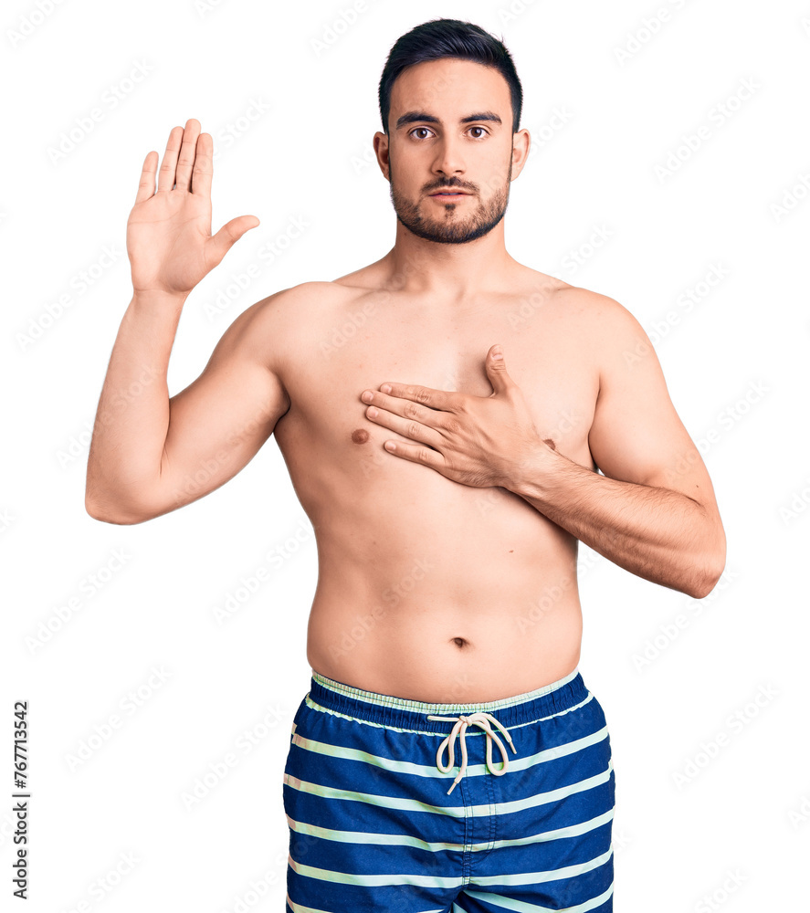 Young handsome man wearing swimwear swearing with hand on chest and open palm, making a loyalty promise oath Young handsome man wearing swimwear swearing with hand on chest and open palm, making a loyalty promise oath