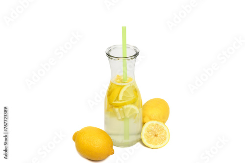 Woda smakowa z cytryną w szklanym dzbanku ze słomką, obok żółte świeże cytrusy