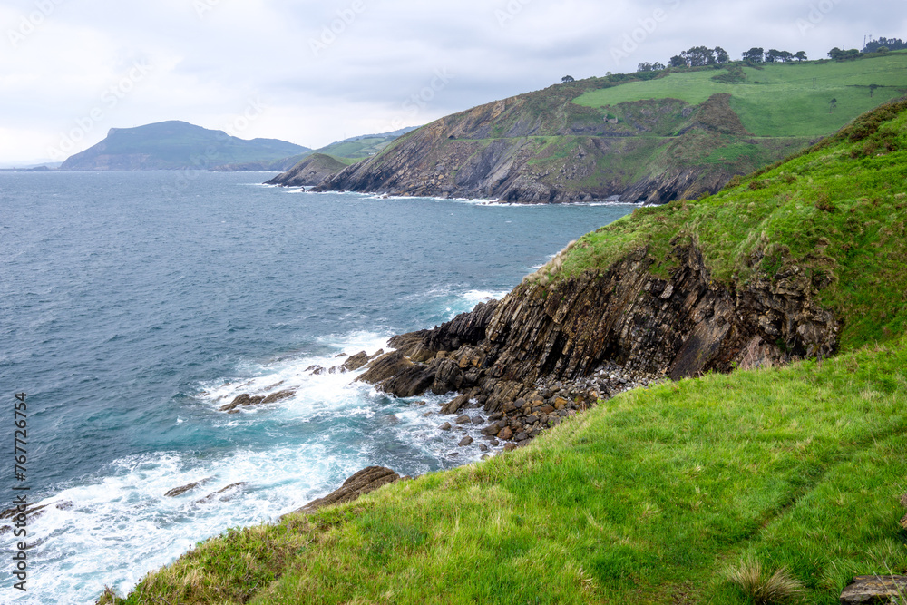 view of the cliffs at the coast of the atlantic ocean in the north of spain and the green meadow