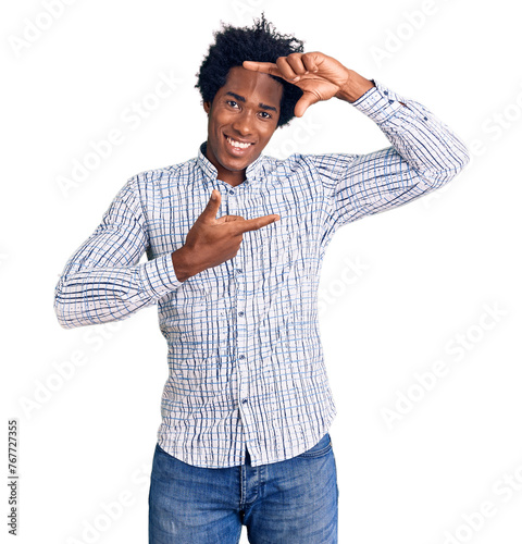 Handsome african american man with afro hair wearing casual clothes smiling making frame with hands and fingers with happy face. creativity and photography concept.
