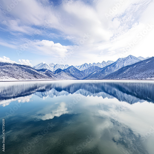 Beautiful winter landscape with snowy mountains reflected in the calm lake.