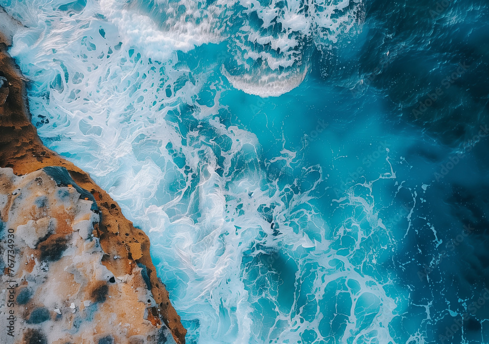 Obraz premium Coastal Majesty: Aerial View of Ocean Blue Waves Crashing on Shoreline Rocks