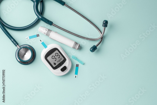 Blood glucose meter, lancet and stethoscope on green background, diabetes concept, top view