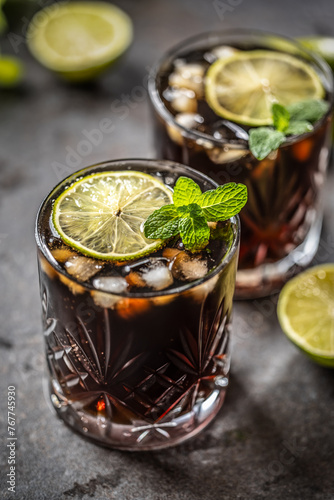 Tropical alcoholic cocktail Cuba Libre composed of white rum, cola, ice cubes, lime and mint