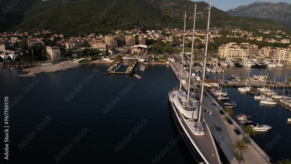 An aerial view of a massive sailboat anchored in a harbor surrounded by urban buildings, lakes, and natural landscapes, showcasing the blend of water and real estate in a city landscape An aerial view of a massive sailboat anchored in a harbor surrounded by urban buildings, lakes, and natural landscapes, showcasing the blend of water and real estate in a city landscape
