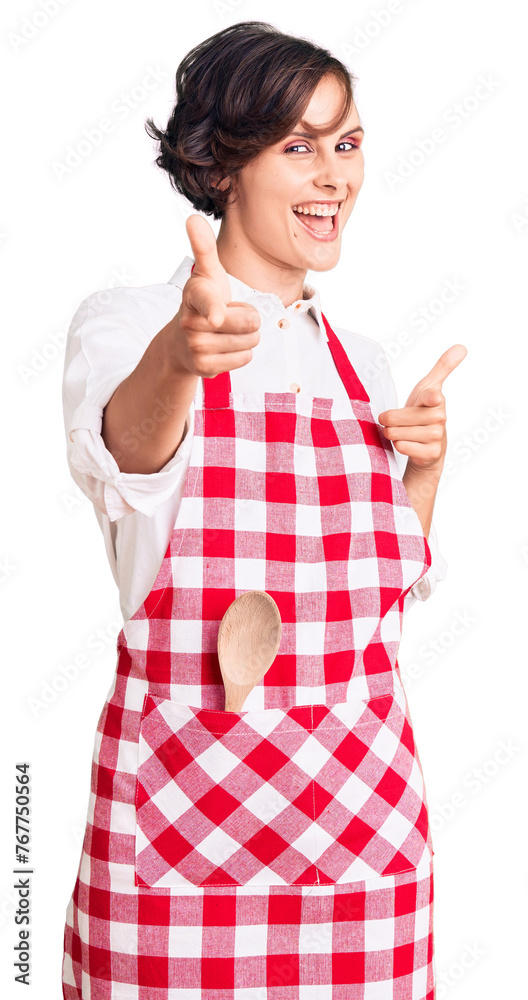 Beautiful young woman with short hair wearing professional cook apron pointing fingers to camera with happy and funny face. good energy and vibes. Beautiful young woman with short hair wearing professional cook apron pointing fingers to camera with happy and funny face. good energy and vibes.