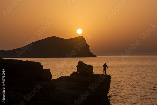 Man fishing at sunset in Cala Comte beach, Joan de Sa Talaia, Ibiza, Balearic Islands, Spain photo