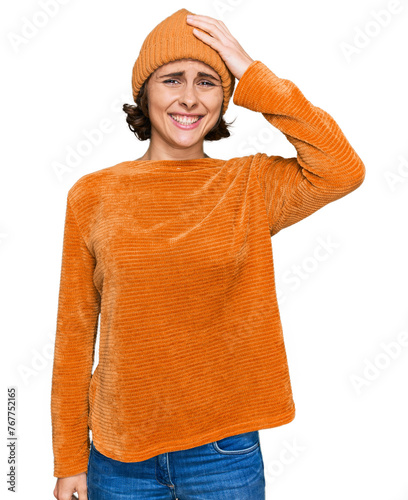 Young hispanic woman wearing casual clothes and wool cap confuse and wonder about question. uncertain with doubt, thinking with hand on head. pensive concept.