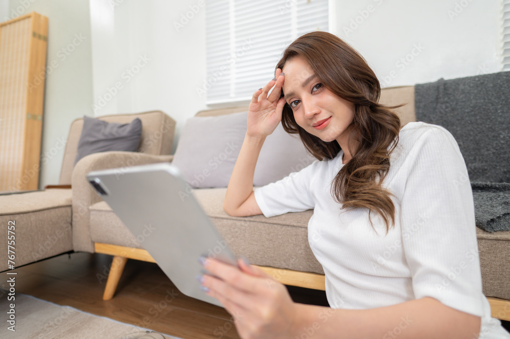 young woman sitting in living room, watching movies on digital tablet, reading on device, enjoying weekend at home young woman sitting in living room, watching movies on digital tablet, reading on device, enjoying weekend at home