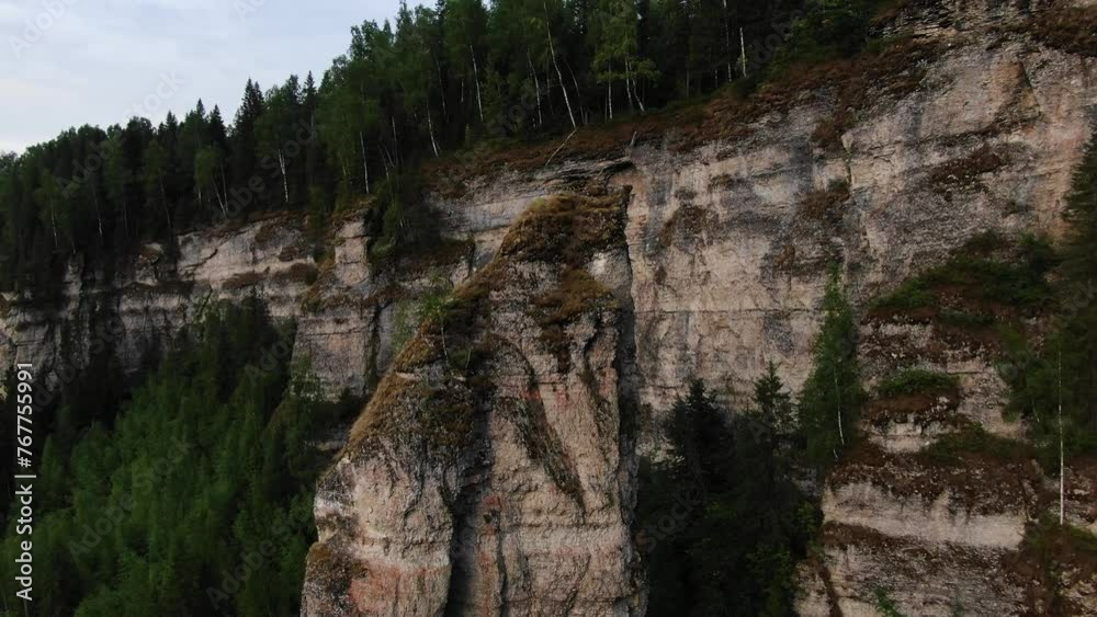 Aerial View of Majestic Forest Cliffs Along Serene River. Departure on a throne that opens up a magnificent panorama of a rocky wall with a coniferous forest and a calm river at sunset. Aerial View of Majestic Forest Cliffs Along Serene River. Departure on a throne that opens up a magnificent panorama of a rocky wall with a coniferous forest and a calm river at sunset.