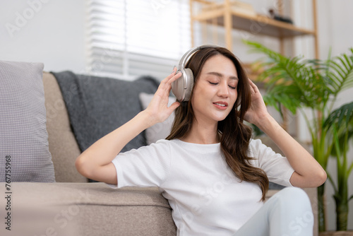 Young woman enjoying her vacation Listen to her favorite songs while relaxing in the living room at home.