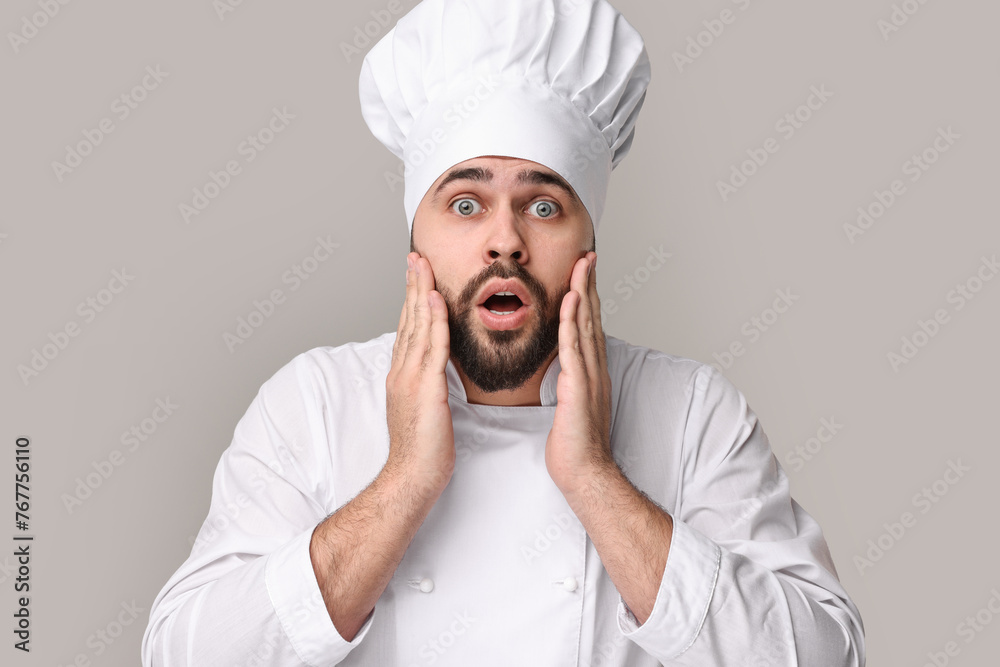 Surprised young chef in uniform on grey background Surprised young chef in uniform on grey background