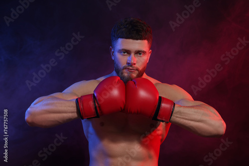 Man wearing boxing gloves on dark background © New Africa