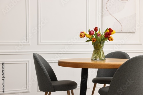 Vase with beautiful tulips on table in dining room