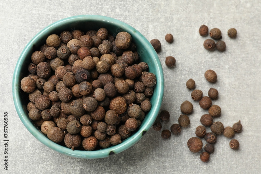 Aromatic allspice pepper grains in bowl on grey table, top view Aromatic allspice pepper grains in bowl on grey table, top view