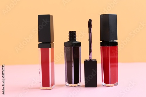 Different lip glosses and applicator on color background
