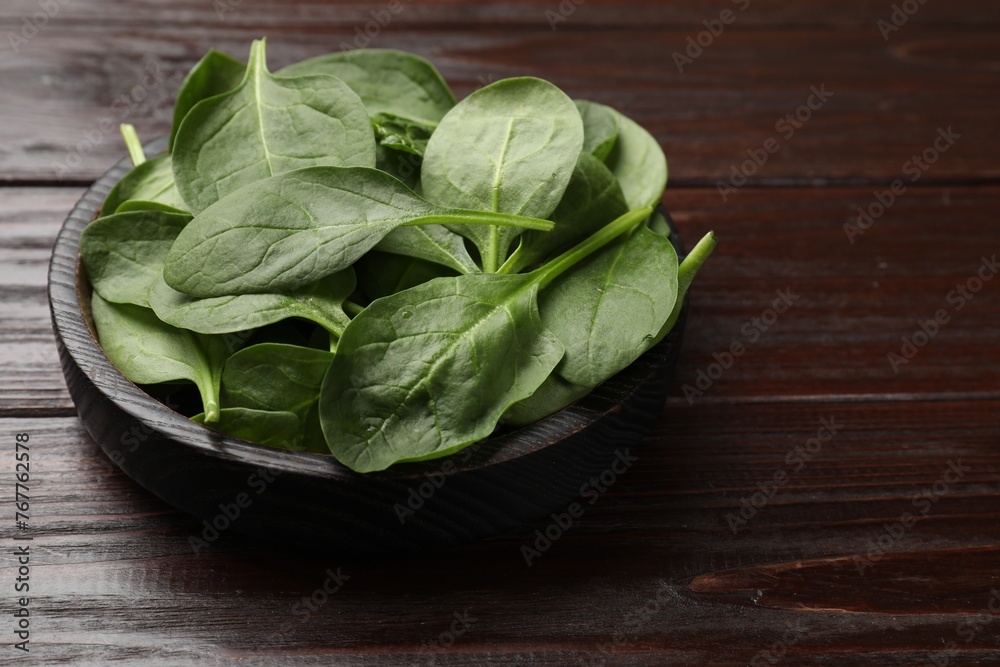Fresh spinach leaves in bowl on wooden table, closeup Fresh spinach leaves in bowl on wooden table, closeup