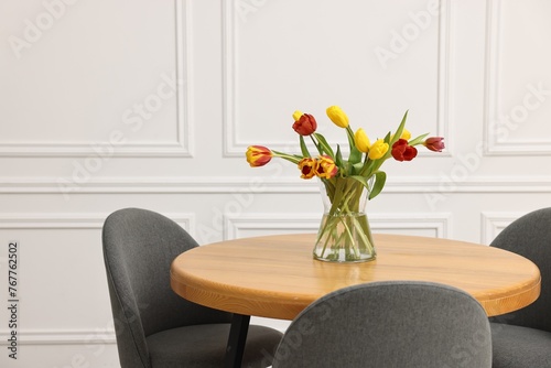 Vase with beautiful tulips on table in dining room