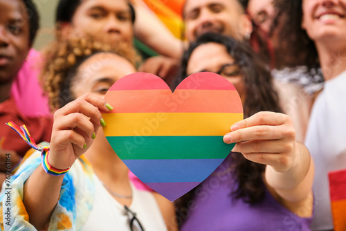 Obraz na płótnie A group of LGBTQ people holding a rainbow heart celebrating International Pride Month. w salonie
