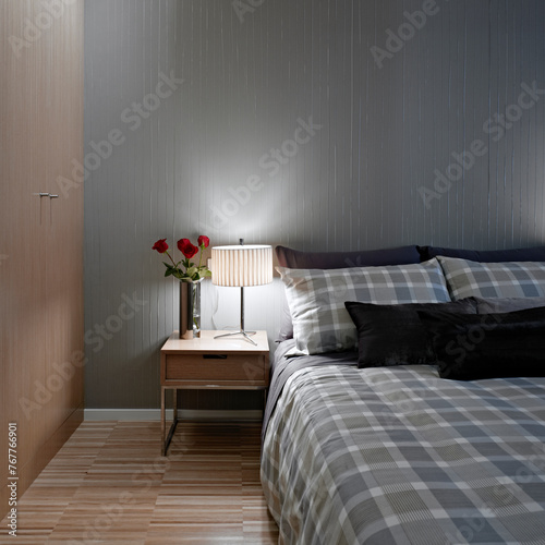 Detalle de un dormitorio con luz encendida y rosas rojas en la mesilla photo