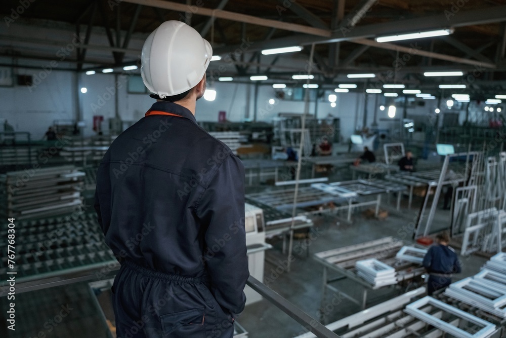 Quality control. Factory worker is indoors with hard hat