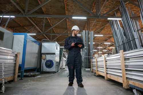 Factory worker is indoors with hard hat