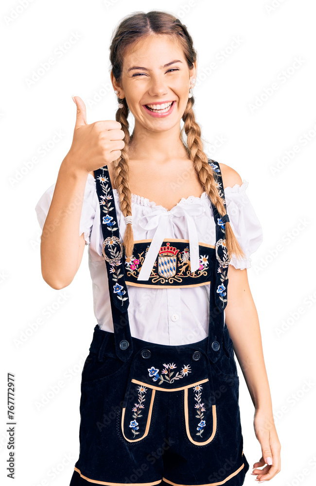 Beautiful caucasian woman with blonde hair wearing octoberfest traditional clothes doing happy thumbs up gesture with hand. approving expression looking at the camera showing success. Beautiful caucasian woman with blonde hair wearing octoberfest traditional clothes doing happy thumbs up gesture with hand. approving expression looking at the camera showing success.