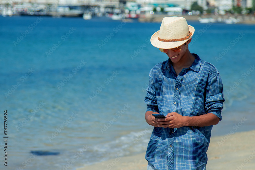 young man looking at his mobile phone on the beach