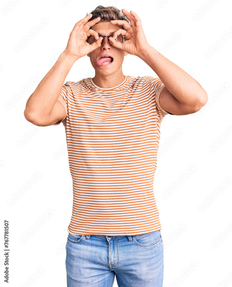 Young handsome man wearing casual clothes and glasses doing ok gesture like binoculars sticking tongue out, eyes looking through fingers. crazy expression. Young handsome man wearing casual clothes and glasses doing ok gesture like binoculars sticking tongue out, eyes looking through fingers. crazy expression.