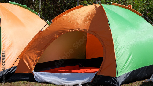 An orange and green camping tent, with its entrance flap opened.