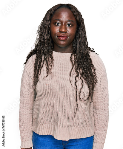 Young african woman wearing wool winter sweater relaxed with serious expression on face. simple and natural looking at the camera.