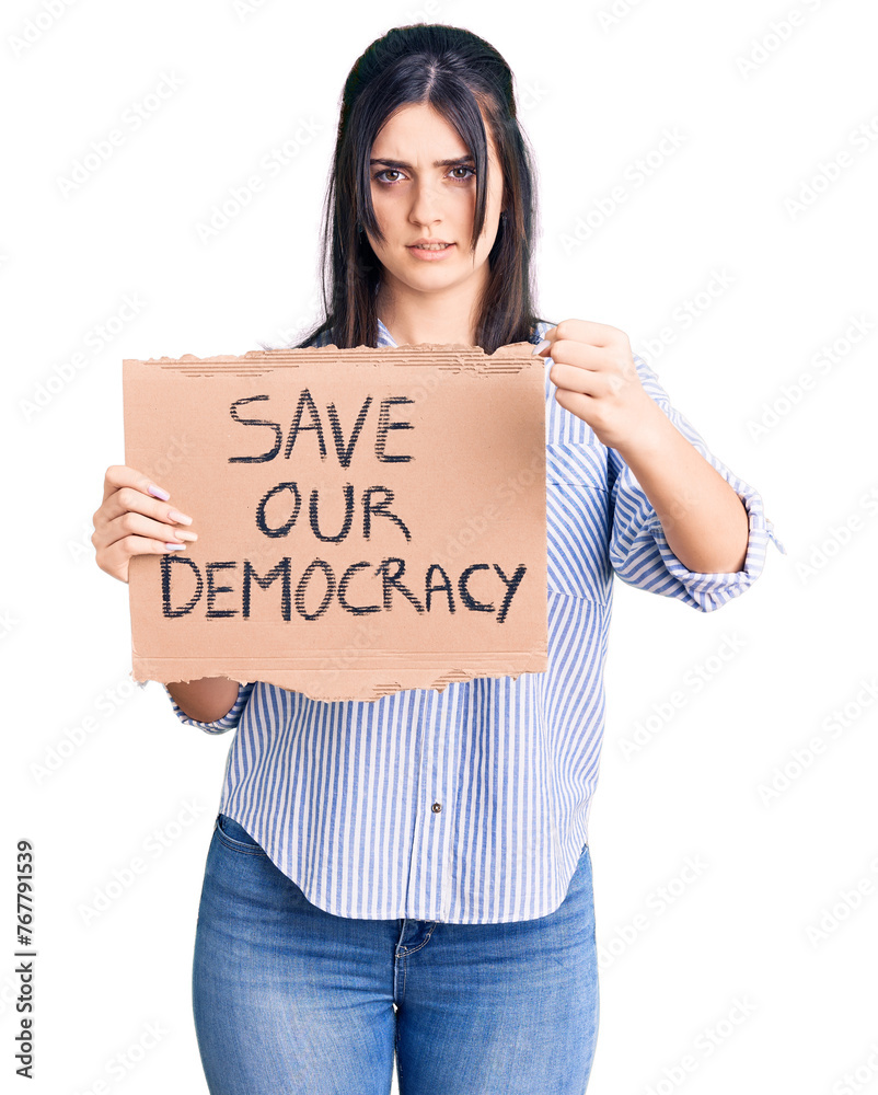 Young beautiful girl holding save our democracy cardboard banner annoyed and frustrated shouting with anger, yelling crazy with anger and hand raised Young beautiful girl holding save our democracy cardboard banner annoyed and frustrated shouting with anger, yelling crazy with anger and hand raised