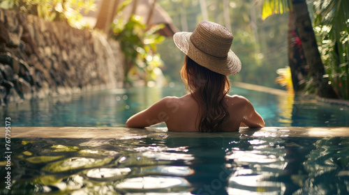 Beautiful woman on vacation relaxing in swimming pool at luxury tropical resort. Back view