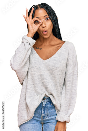 Beautiful hispanic woman wearing casual clothes doing ok gesture shocked with surprised face, eye looking through fingers. unbelieving expression.