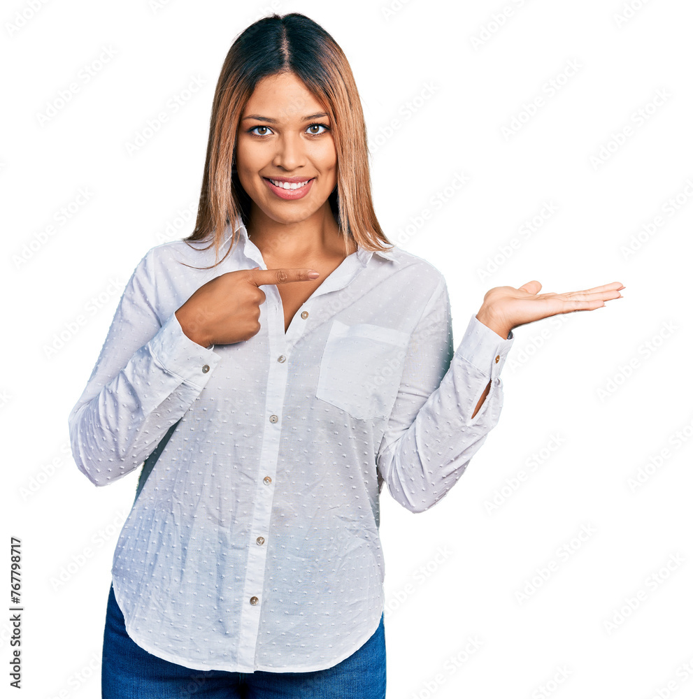 Young hispanic woman wearing casual white shirt amazed and smiling to the camera while presenting with hand and pointing with finger. Young hispanic woman wearing casual white shirt amazed and smiling to the camera while presenting with hand and pointing with finger.