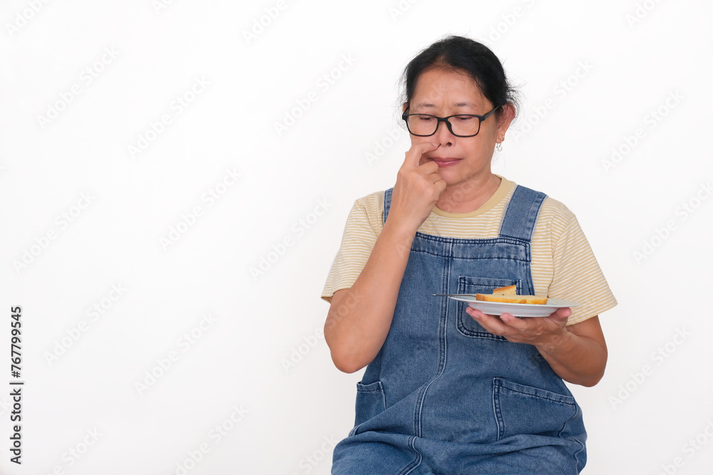 Asian housewife sitting alone holding sandwich on a plate, losing appetite for breakfast Asian housewife sitting alone holding sandwich on a plate, losing appetite for breakfast
