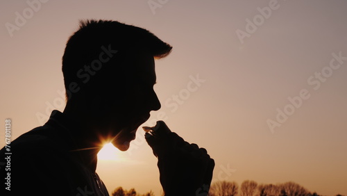 Profile of a man eating an appetizing burger at sunset