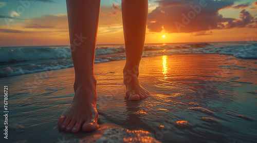 Closeup of feet on beach  with sunset reflections illuminating the water