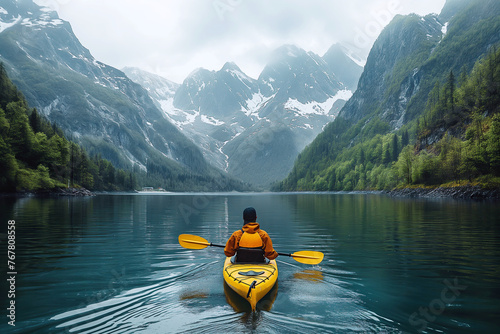 back of girl kayaker kayaking on lake with a scene of snowy peaks mountains and forest
