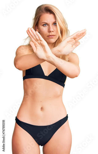 Young beautiful blonde woman wearing bikini rejection expression crossing arms doing negative sign, angry face © Krakenimages.com