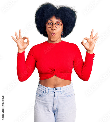 Quadro su tela Young african american girl wearing casual clothes and glasses looking surprised and shocked doing ok approval symbol with fingers