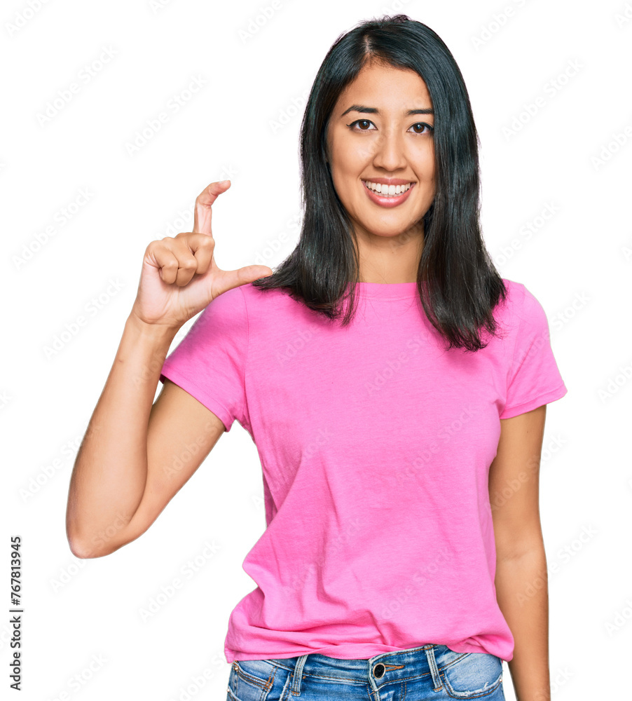 Beautiful asian young woman wearing casual pink t shirt smiling and confident gesturing with hand doing small size sign with fingers looking and the camera. measure concept. Beautiful asian young woman wearing casual pink t shirt smiling and confident gesturing with hand doing small size sign with fingers looking and the camera. measure concept.