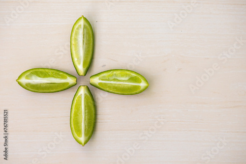 Four slices of a green lemon (Citrus limon) are isolated on a wooden background. In the Bengali language, it is called Lebu.  photo