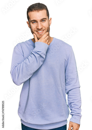 Young caucasian man wearing casual clothes looking confident at the camera smiling with crossed arms and hand raised on chin. thinking positive.