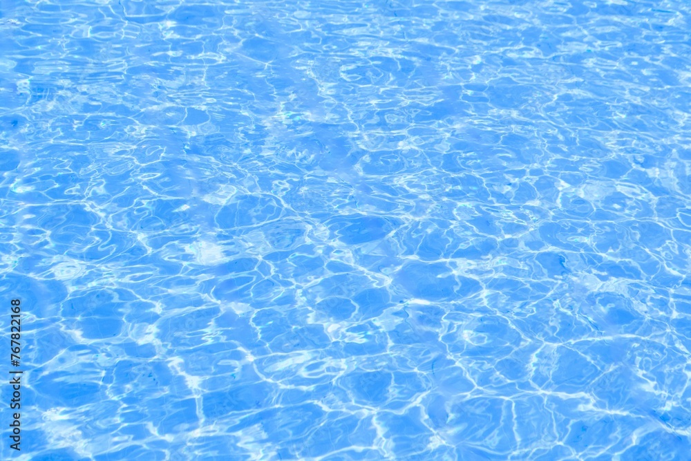 Obraz premium Blue water surface. Reflection of Sun in Water ripple surface texture. Blue clean water wave with splashes and bubbles. Natural summer banner background 