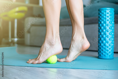 Myofascial relaxation of the muscles of the foot with a massage tennis on a mat at home, close-up. 