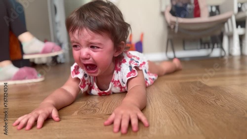 baby is crying lying on the floor. happy family child dream concept. sad small baby girl lies on the floor indoors and cries a lot, the child is naughty lifestyle. baby crying