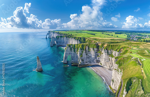 A panoramic view of the rugged cliffs and lush green meadows at etretat, with clear blue waters below, a golf course in the distance, and a quaint village nestled on its path to coastline