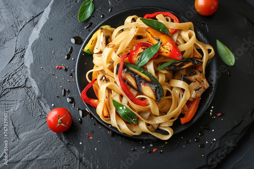 spaghetti with vegetables in black plate, top view