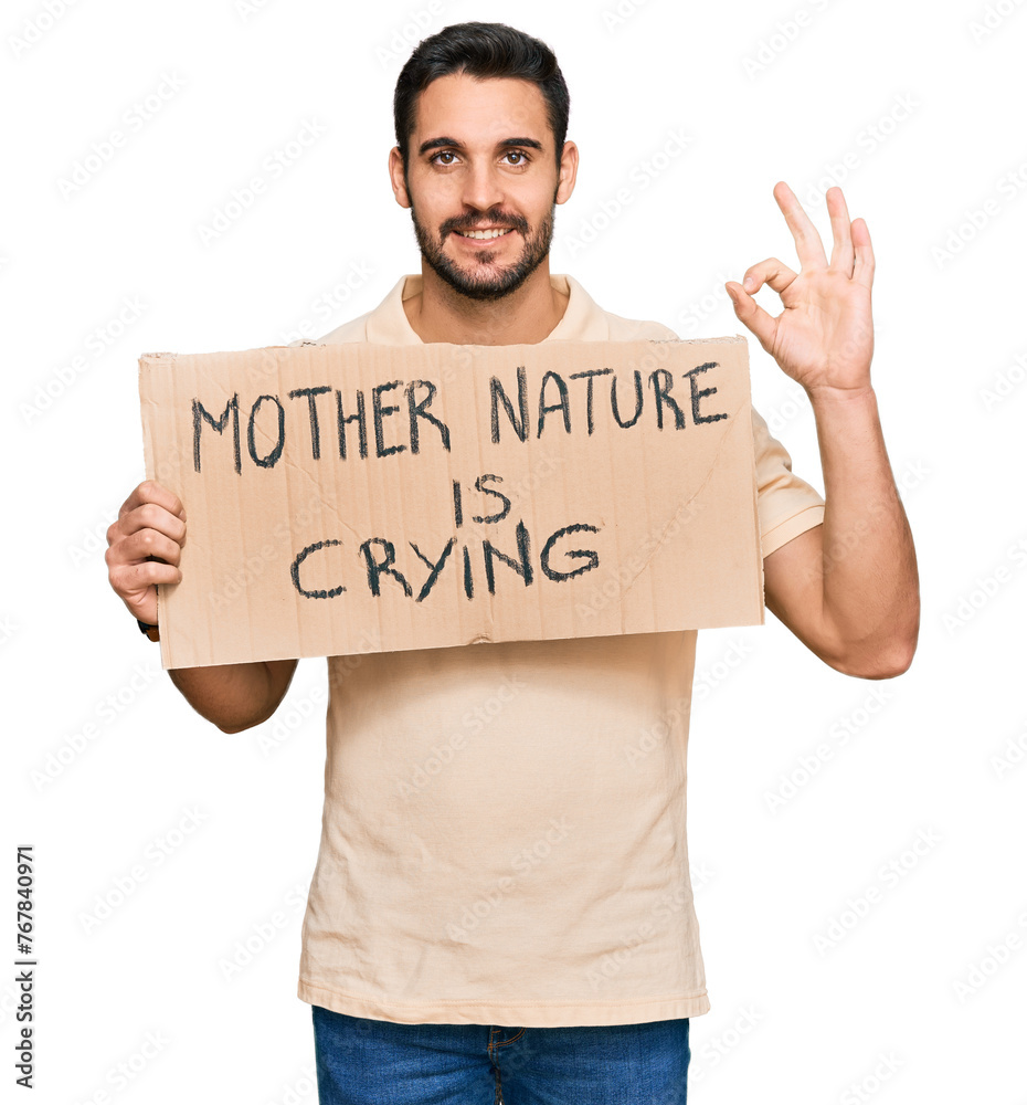 Young hispanic man holding mother nature is crying protest cardboard banner doing ok sign with fingers, smiling friendly gesturing excellent symbol Young hispanic man holding mother nature is crying protest cardboard banner doing ok sign with fingers, smiling friendly gesturing excellent symbol